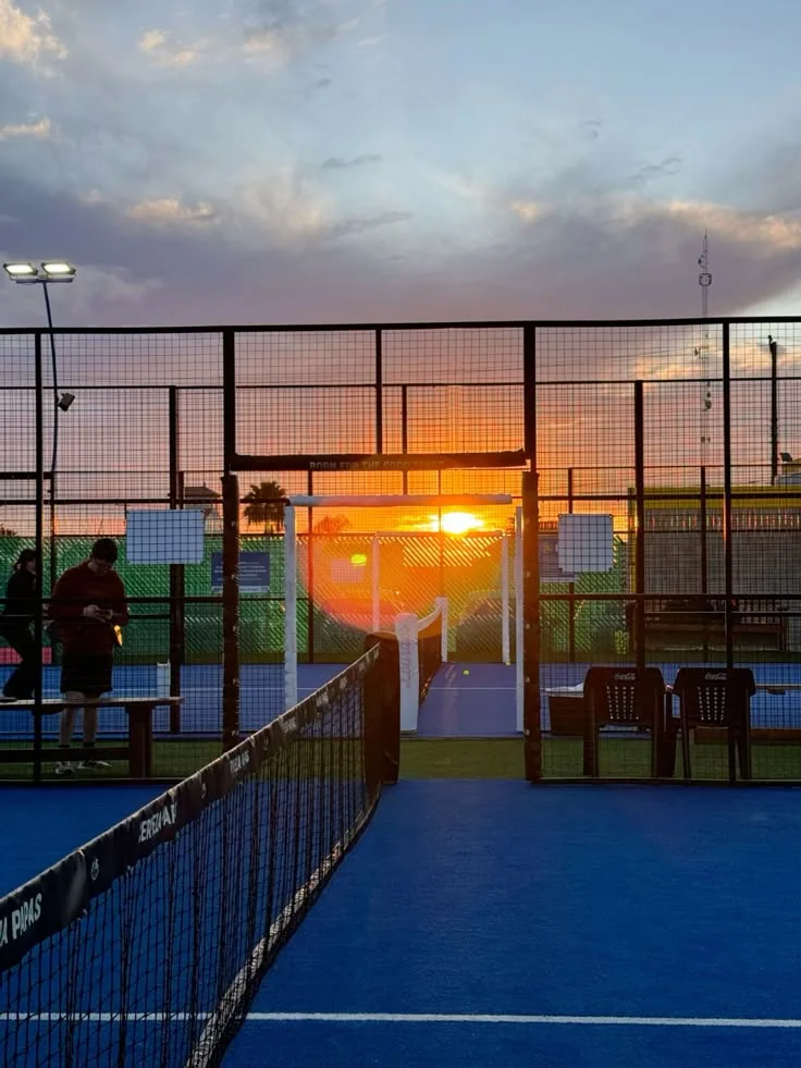 Atardecer a través de la red de una pista de pádel