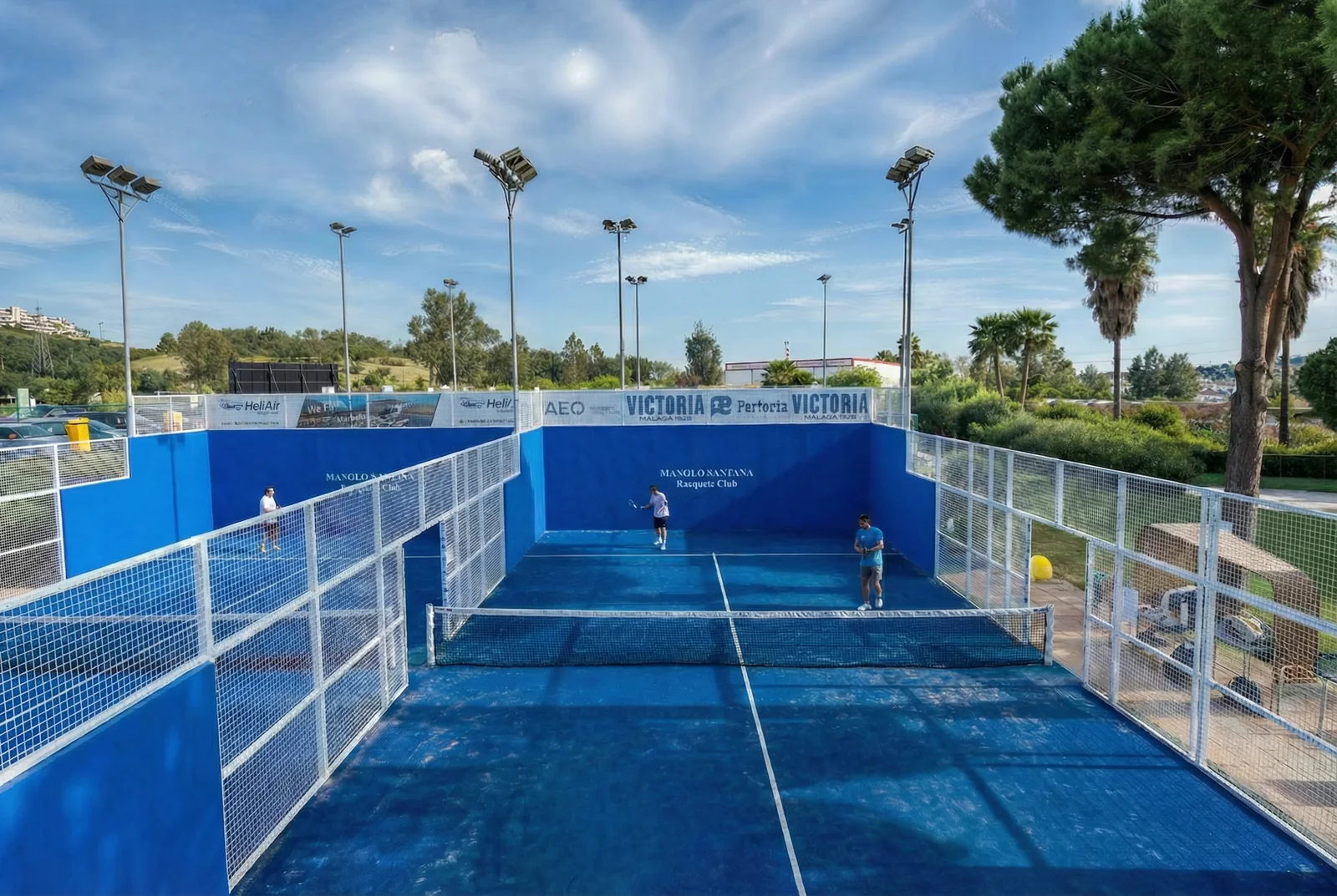 Pistas de pádel del club rodeadas de pinos y palmeras